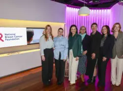 Seven people from the National Breast Cancer Foundation (NBCF) Team smiling next to the NBCF logo