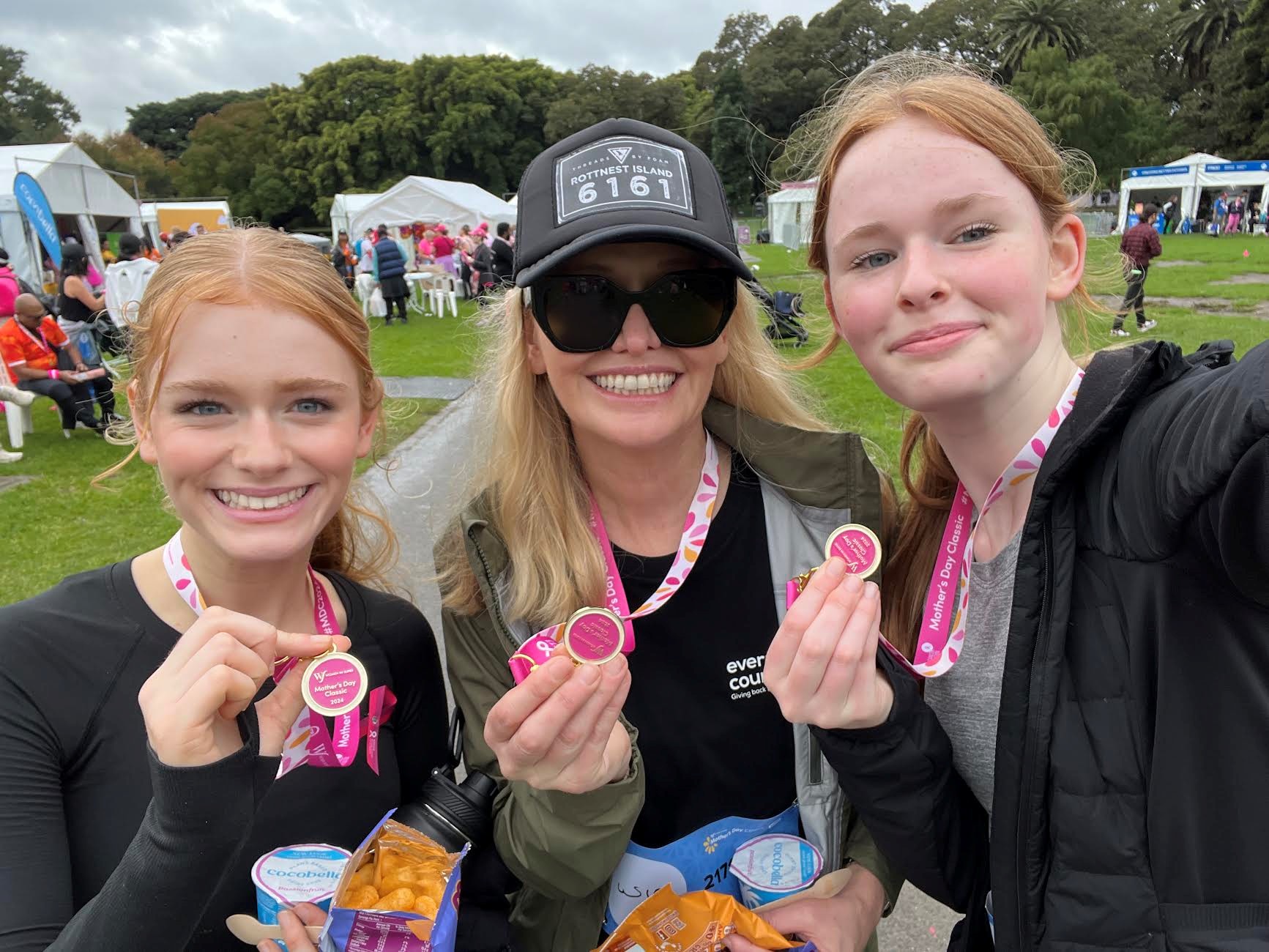 Three NBCF supporters smiling and holding up pink medals at the Mother's Day Classic